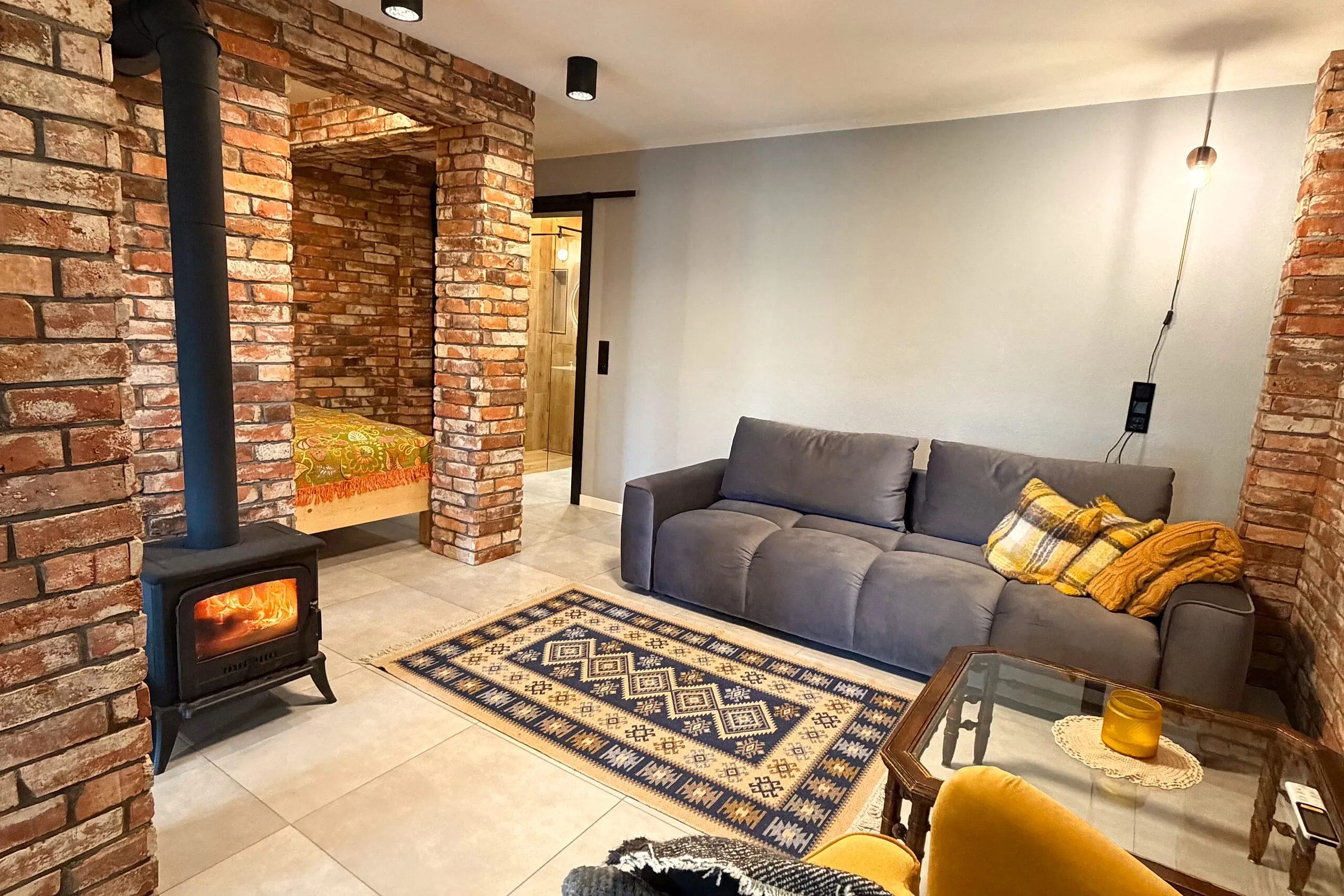 Apartament 3 – salon z rozkładaną kanapą i kominkiem typu „koza”